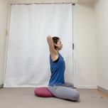 お尻の下にクッションを敷き、左手を後頭部に添えて脇を開いたあぐらの体勢
