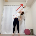 足を腰幅～肩幅程度に開き、左手を斜め右上に伸ばして左体側を伸ばして立った体勢