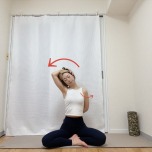 右手を背中に回し、左手を右こめかみに添えて頭を左に傾ける首筋・肩・肩甲骨周りのストレッチ