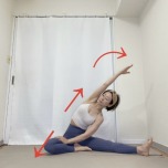 右脚を横に伸ばした片足開脚から右手を左ももに添え、左手を右斜め上に伸ばして上体を右に傾けた左体側のストレッチ