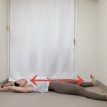 仰向けで両手を頭の腕で組み、かかとを突き出して全身を伸ばすストレッチ
