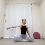 あぐらで座り、横に伸ばした左腕を内側にねじるストレッチ