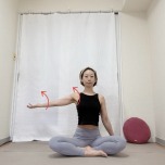 あぐらで座り、横に伸ばした左腕を外側にねじるストレッチ