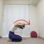 頭の後ろで左肘を右手で掴んだ正座から背骨を丸めて上体を前に傾けた体勢