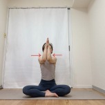 あぐらで座り、腕を90度に曲げて胸の前で両肘から手のひらを寄せ合い、肩甲骨を左右へ開いた体勢