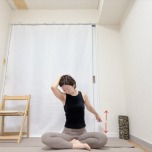 あぐらで座り、左手を後頭部に添えて頭を左下に傾け、後ろに引いた右腕を上下に動かす肩まわりのストレッチ。