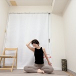 あぐらで座り、左手を後頭部に添えて頭を左下に傾け、後ろに引いた右腕後ろに引いた右腕を前後にひねる肩まわりのストレッチ