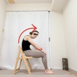 両手を膝の方に滑らせて背中を丸める、椅子に座って行うキャットポーズストレッチ