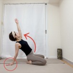 正座から左手を後ろの床に着き、右手を斜め上に伸ばして胸を開くラクダのポーズ